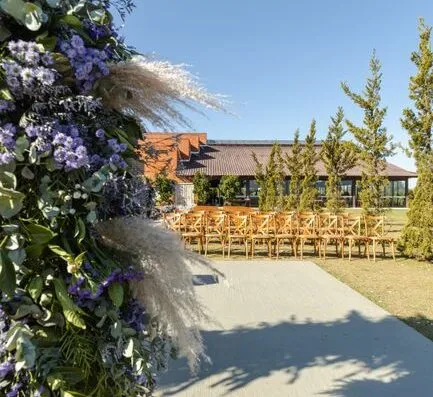 Hermosa decoración de boda al aire libre con decoración floral y sillas de madera bajo un cielo despejado.