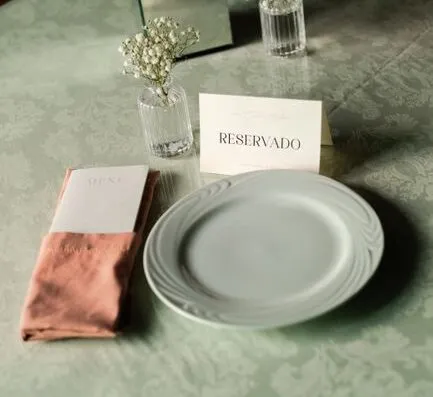 Mesa de boda bellamente preparada con tarjeta 'Reservado', centro de mesa floral y vajilla elegante.
