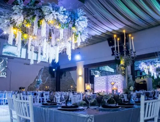 Lujoso lugar de bodas en interiores en León, México, con un exquisito candelabro floral y elegantes arreglos de mesa.