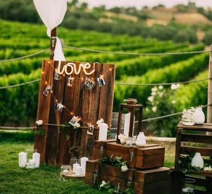 Encantadora configuración rústica de boda con acentos de madera y decoración de velas en un entorno de viñedo.