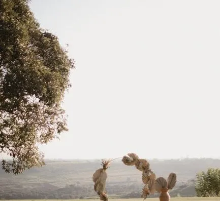 Hermoso montaje de boda al aire libre con arco floral en un paisaje soleado, perfecto para ceremonias románticas.