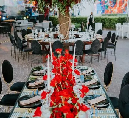 Estilo de cena de comedor al aire libre con rosas rojas y vajilla elegante para una recepción de evento lujosa.