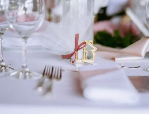Una mesa de boda bellamente dispuesta con cubiertos elegantes y cristalería, adornada con elementos decorativos.