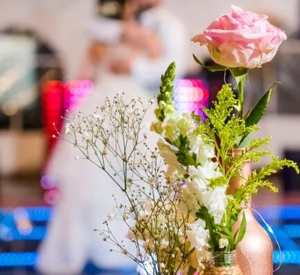 Hermoso arreglo floral en una boda con una pareja bailando de fondo.