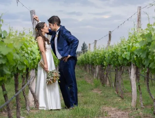 La novia y el novio comparten un momento romántico en un viñedo exuberante en Luján de Cuyo, Mendoza.