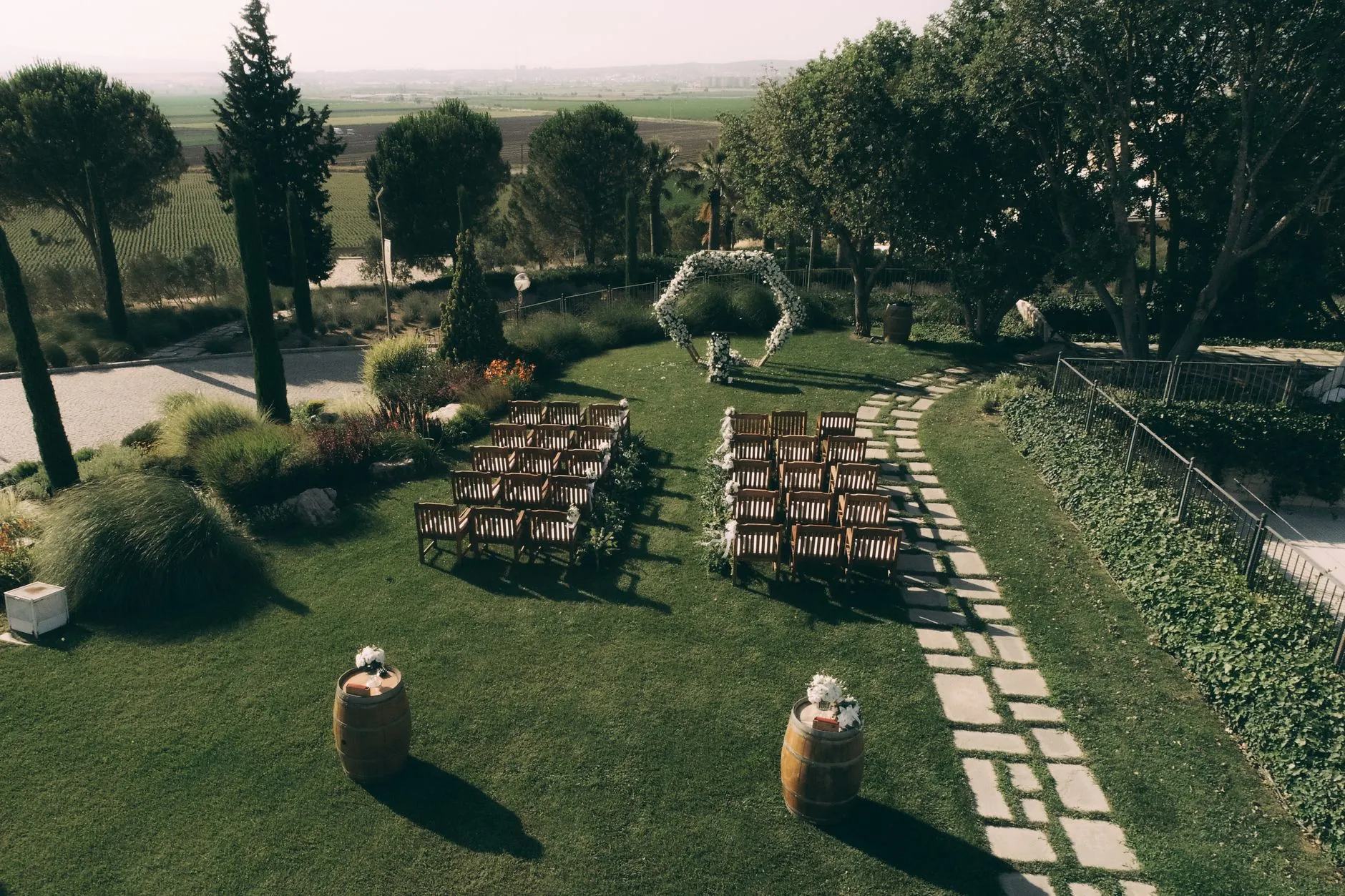 Un hermoso entorno de boda en jardín con sillas de madera y un arco floral en Torbalı, Turquía.