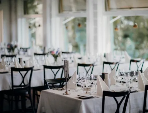 Mesas de comedor bellamente decoradas, perfectas para una recepción de boda o evento formal de cena, capturadas en el interior.