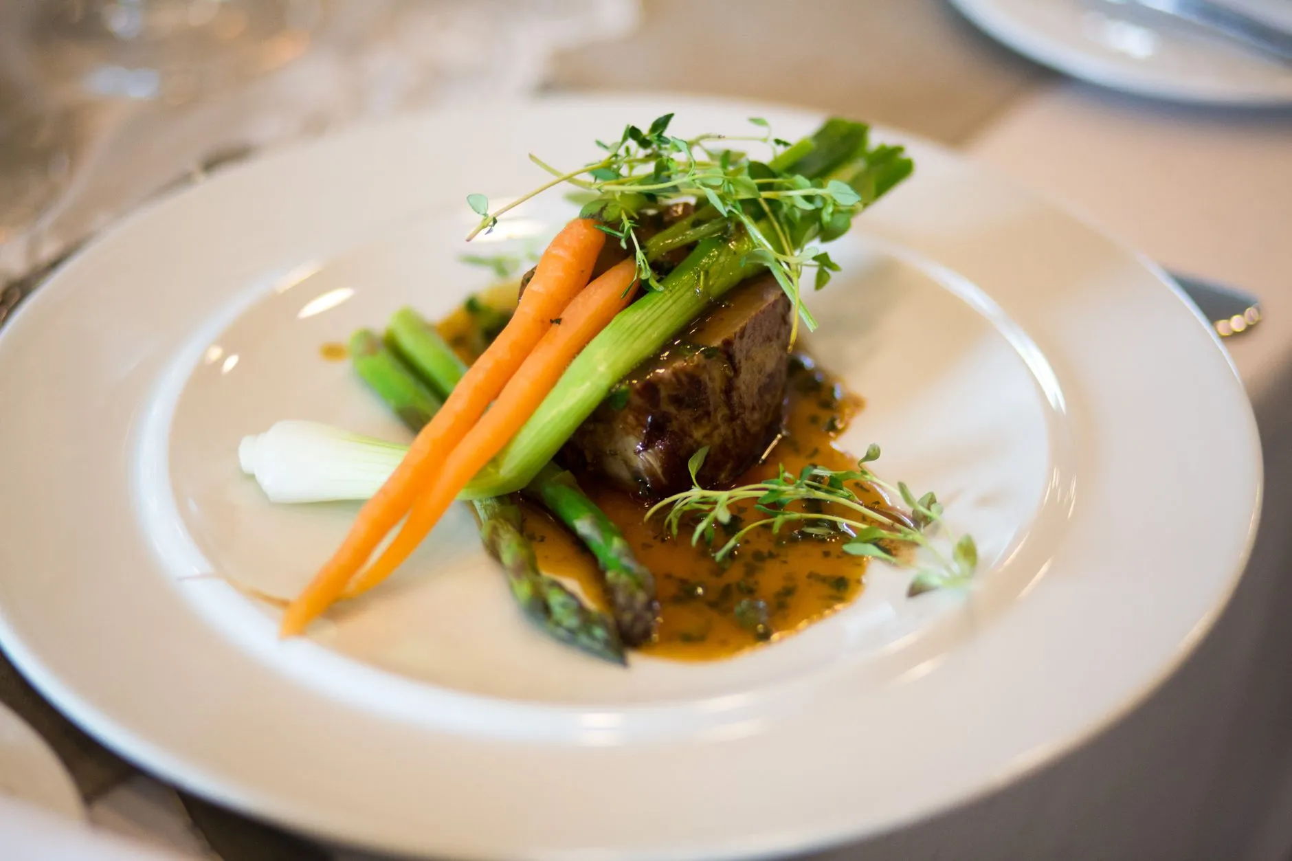 Comida gourmet lujosa elegantemente presentada con verduras y salsa.