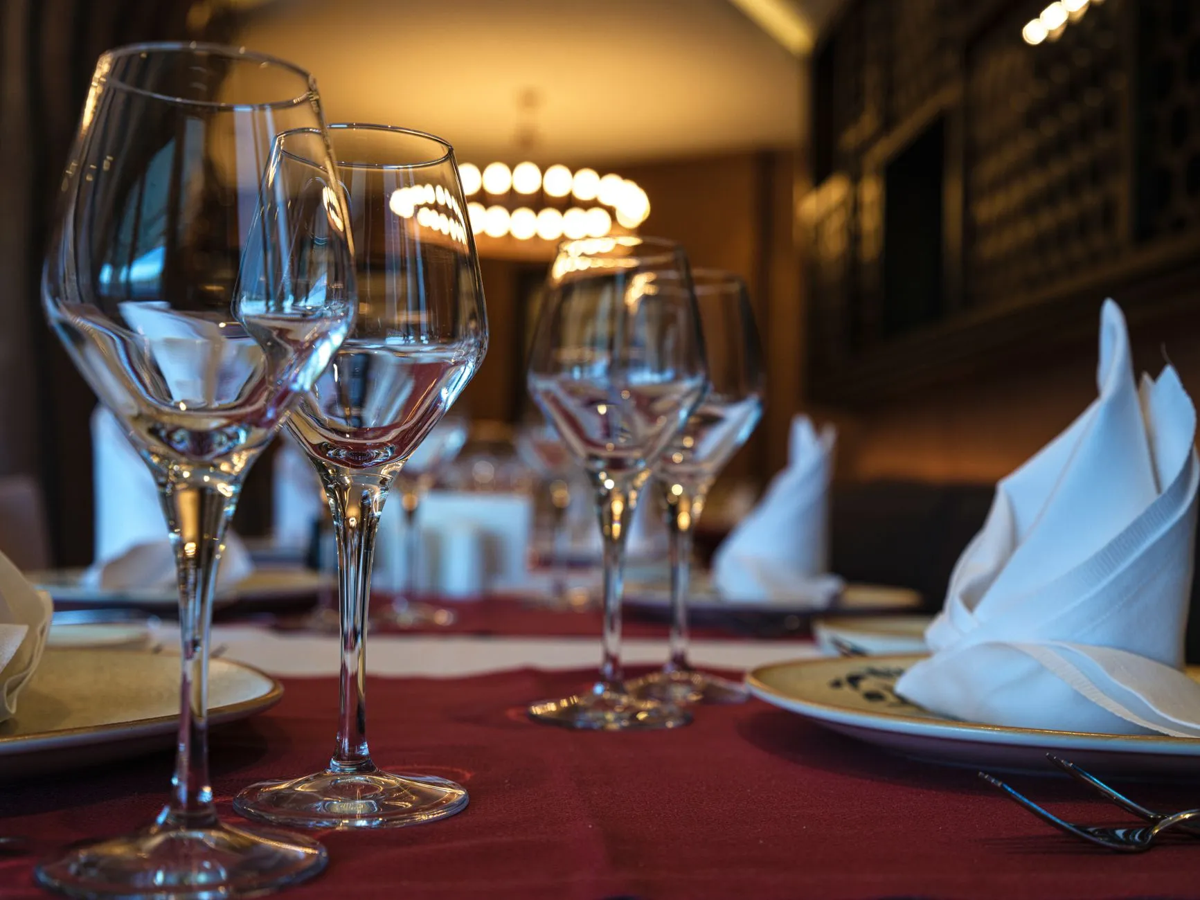 Primer plano de una mesa de cena bien puesta con copas de vino y servilletas dobladas, lista para una experiencia de alta cocina.