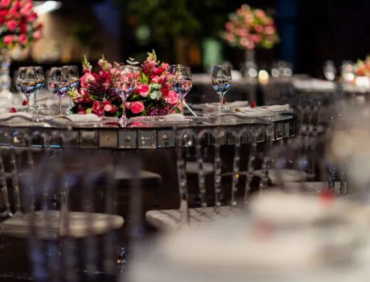 Montaje de mesa lujoso para recepción de boda con centro de mesa floral rosa y cristalería.