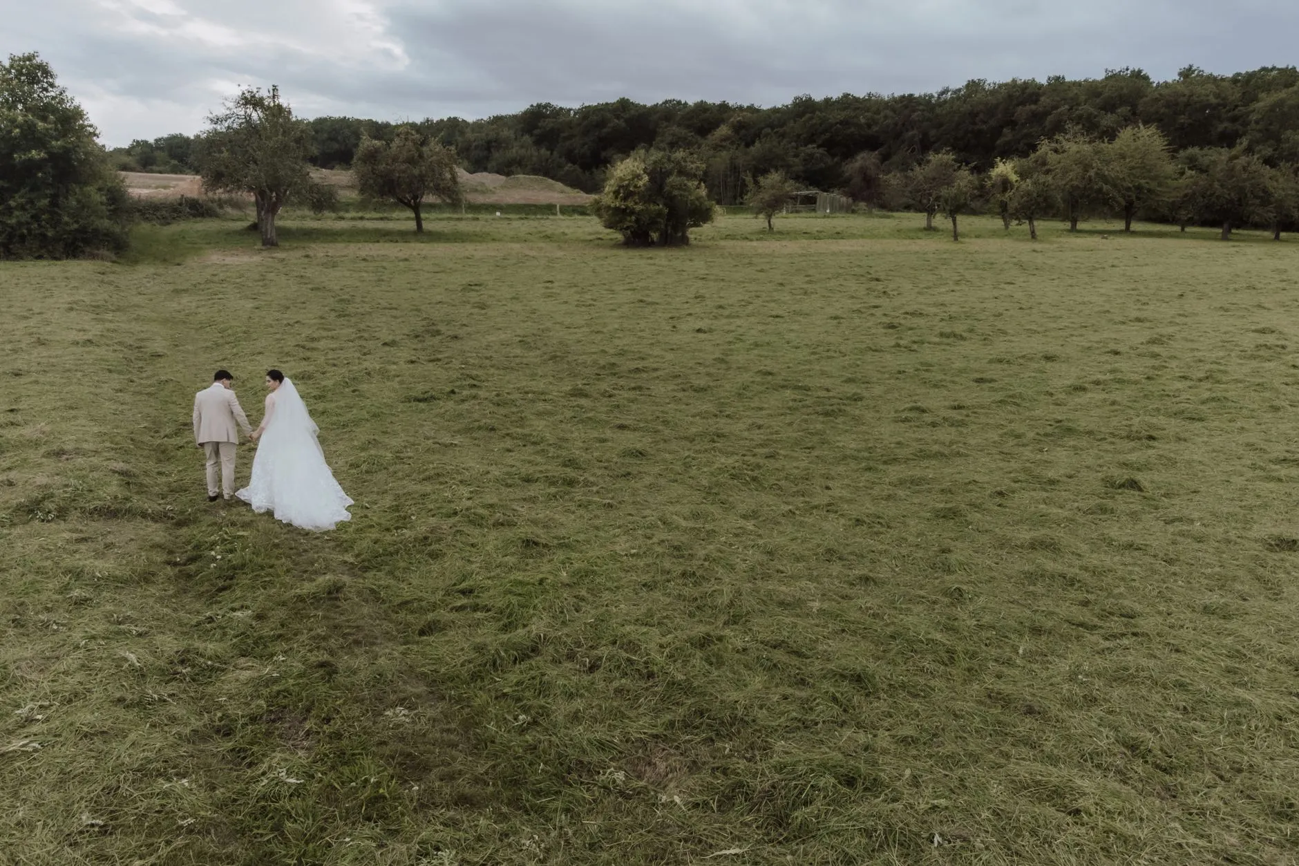 Vista aérea de una pareja recién casada caminando por un entorno campestre sereno (imagen de referencia)