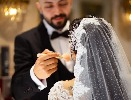 Una novia recibe un retoque de maquillaje por parte del novio antes de la ceremonia de boda.