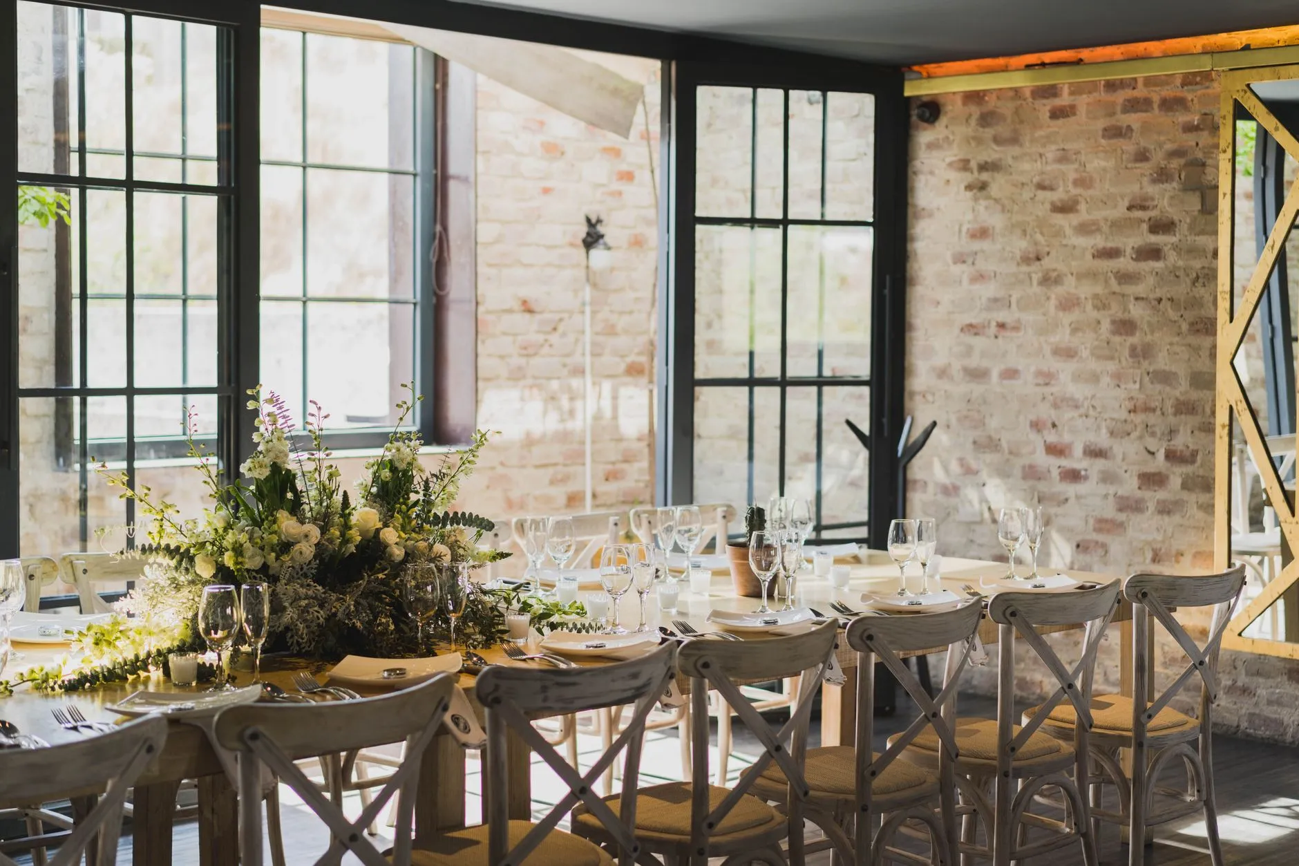 Configuración de mesa elegante en un restaurante de León, con centro de mesa floral y luz natural (imagen de referencia)