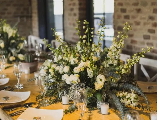 Mesa de recepción de boda sofisticada con flores blancas y vajilla elegante.
