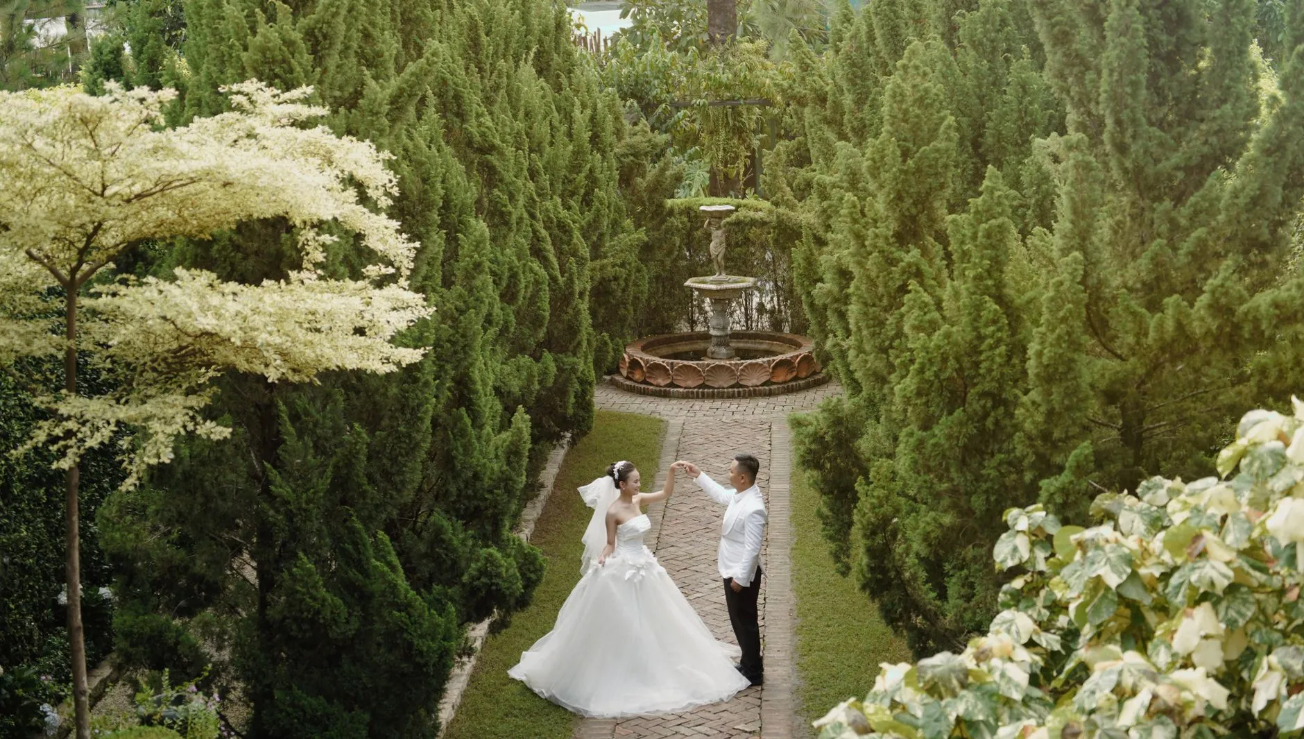 Pareja de boda elegante bailando en un jardín exuberante en Ciudad Ho Chi Minh.