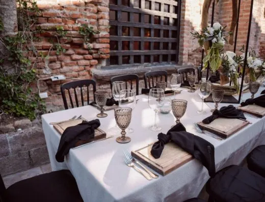 Mesa de boda al aire libre bellamente dispuesta con decoración floral y vajilla elegante, ideal para un evento sofisticado.