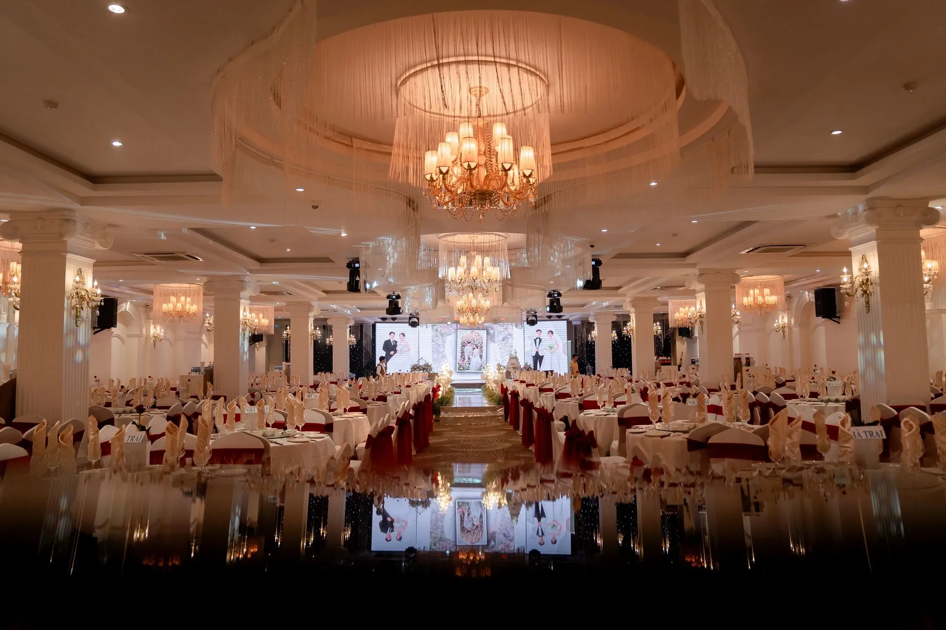 Salón lujoso bellamente organizado para un gran evento nocturno, con candelabros iluminando la decoración.
