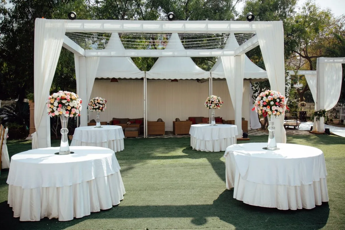 Encantador arreglo de boda al aire libre con pérgolas cubiertas de blanco y centros de mesa florales bajo un cielo soleado (imagen de referencia)