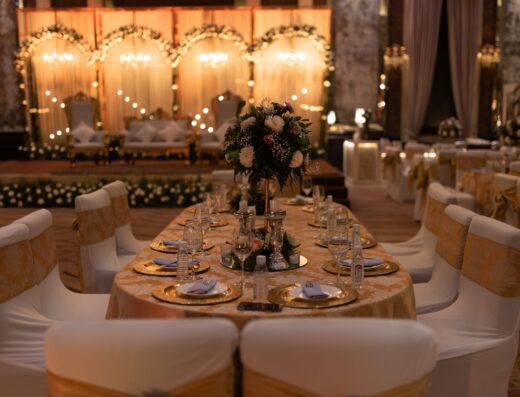 Un salón de recepción de boda bellamente decorado con arreglos florales y una iluminación elegante.