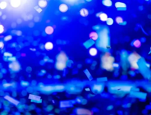 Una toma dinámica de confeti de colores y luces bokeh azules, que captura una atmósfera festiva.