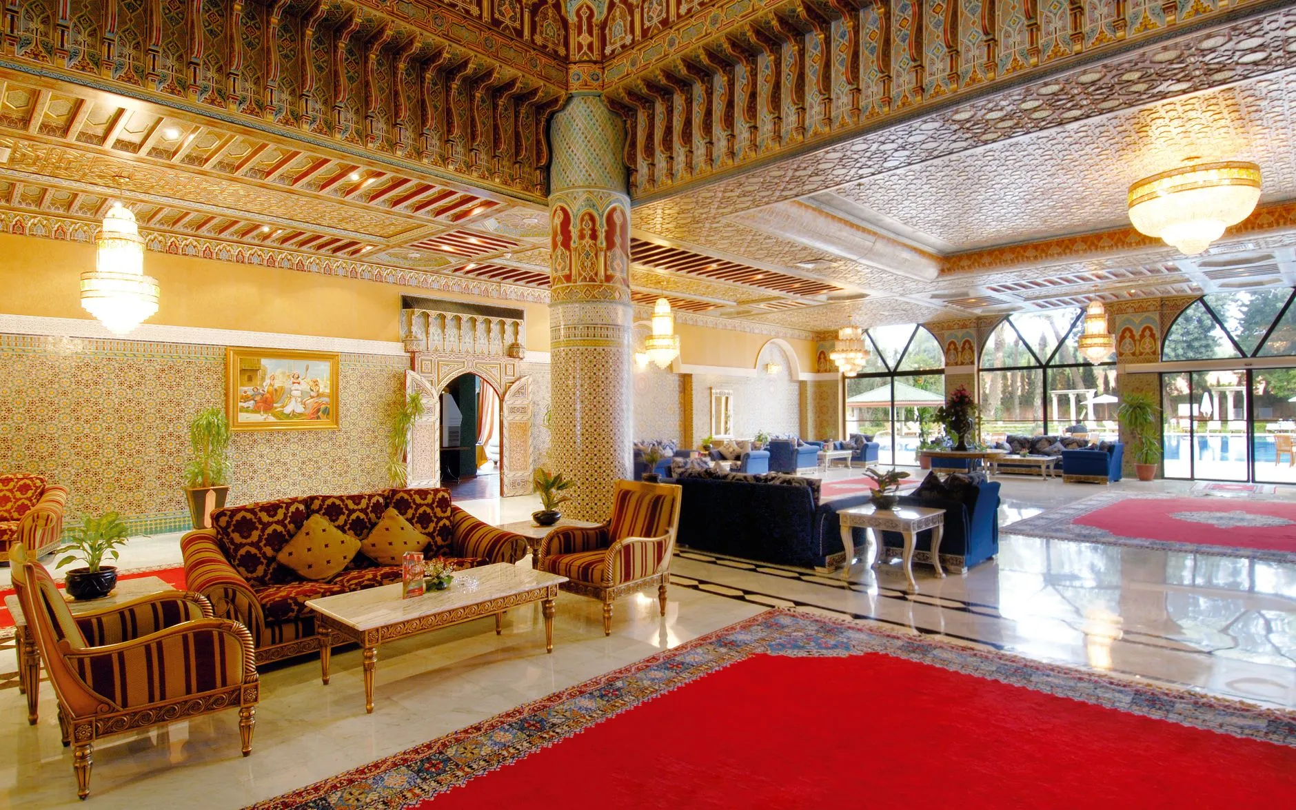 Lobby de hotel marroquí sofisticado con decoración ornamentada, asientos acolchados y candelabros.