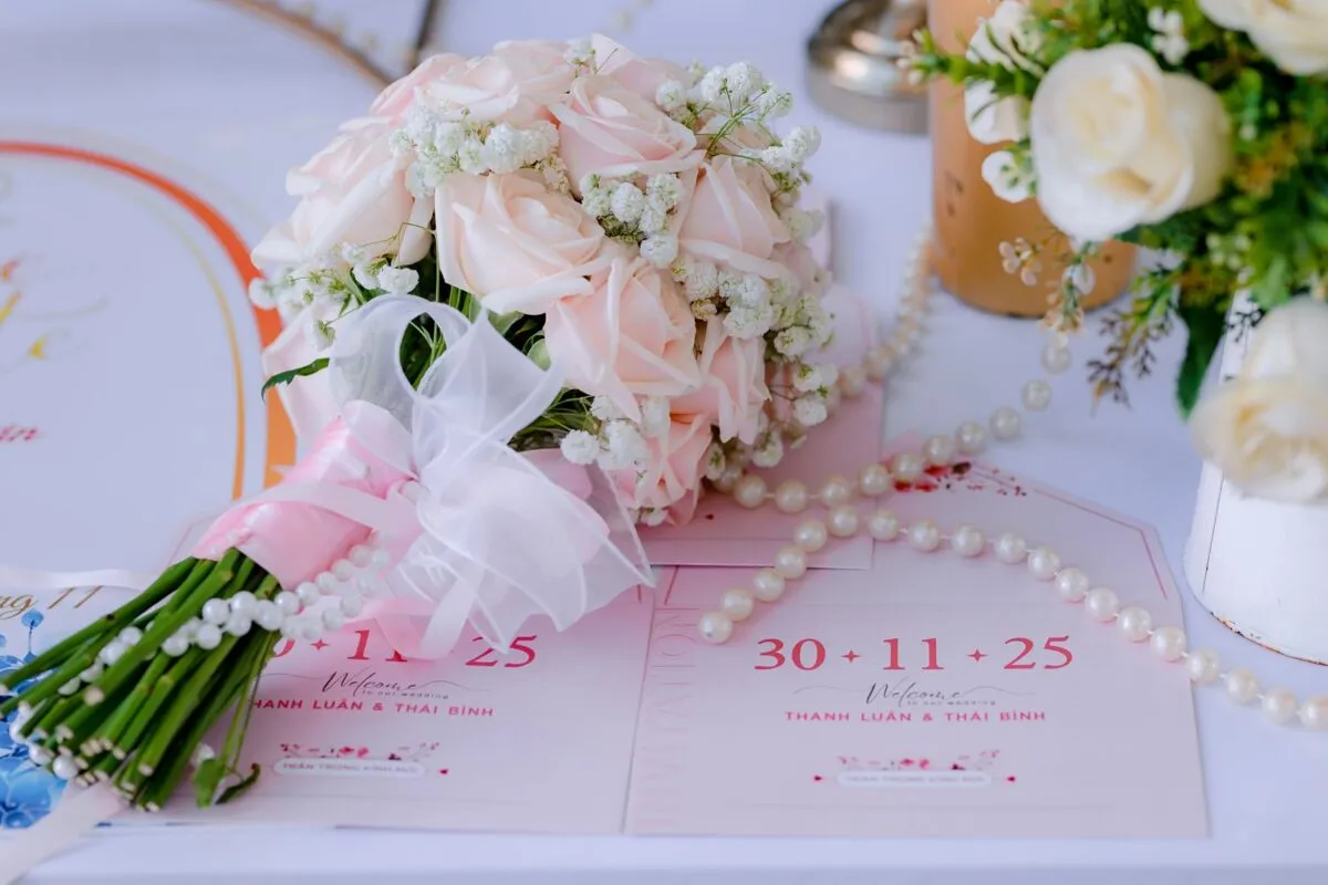 Delicado ramo de rosas rosadas con invitaciones de boda sobre una mesa, perfecto para un entorno de boda romántico (imagen de referencia)