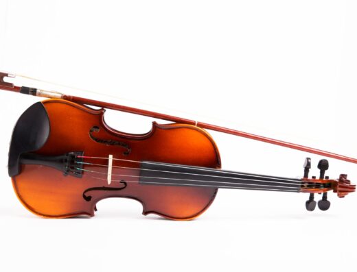 Un violín clásico de madera descansando con su arco, bellamente capturado sobre un fondo blanco.