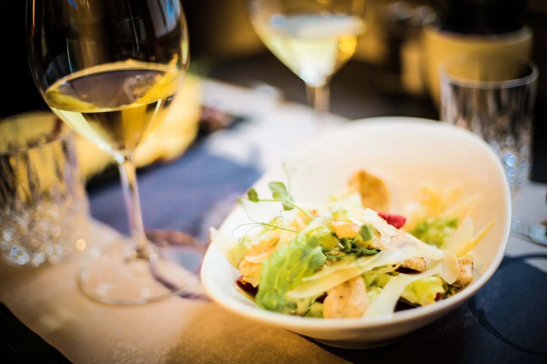 Un elegante ambiente gastronómico con una ensalada fresca y vino blanco, perfecto para una comida gourmet.