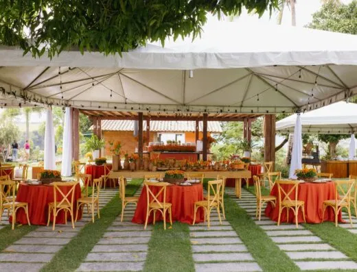 Precioso montaje para una boda al aire libre con decoración en rojo y naranja bajo un dosel blanco.