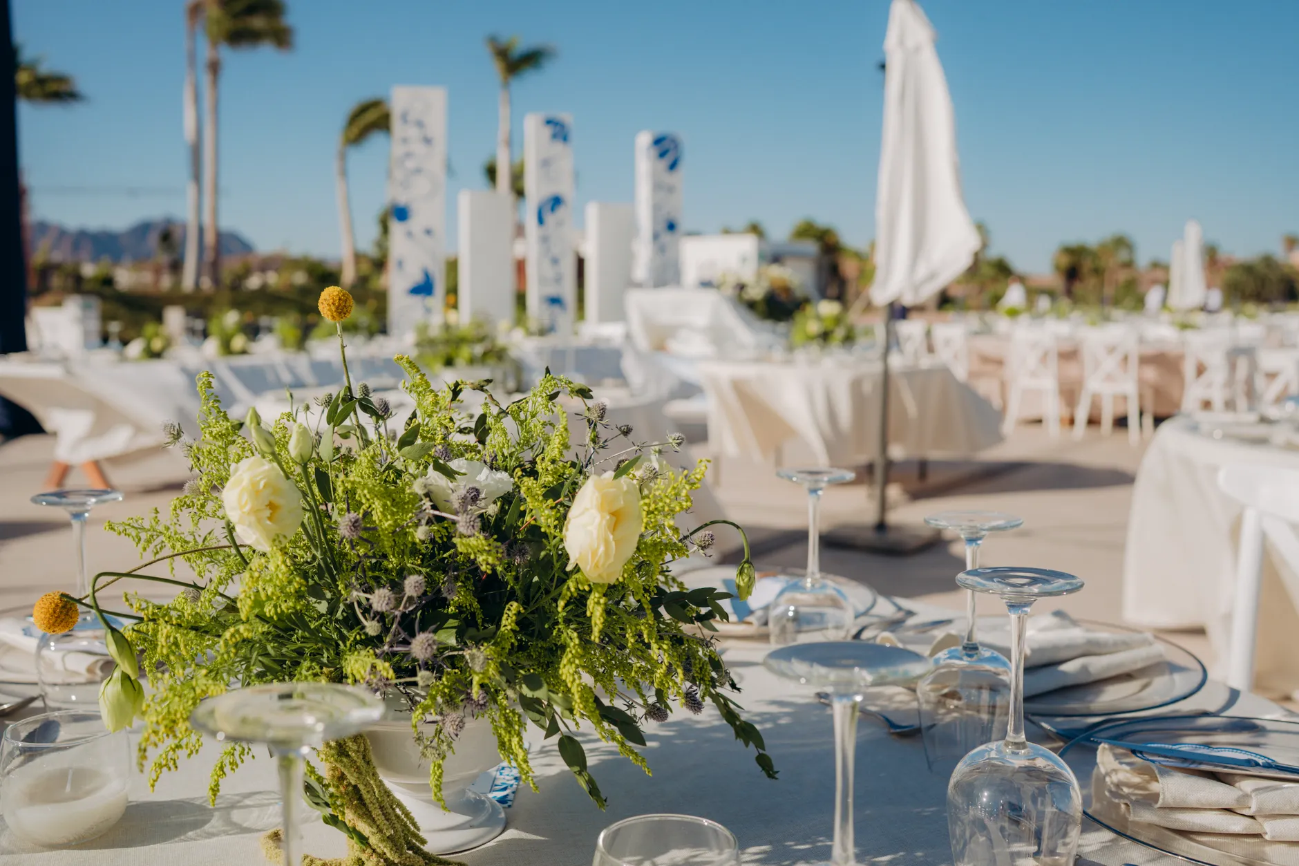 Sofisticada escena de boda al aire libre con arreglos florales y elegante montaje de mesas.