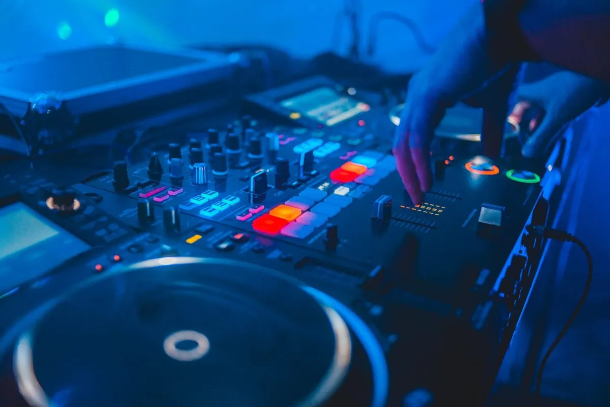 Toma vibrante de un mezclador de DJ en uso en una discoteca con luces coloridas (imagen de referencia)