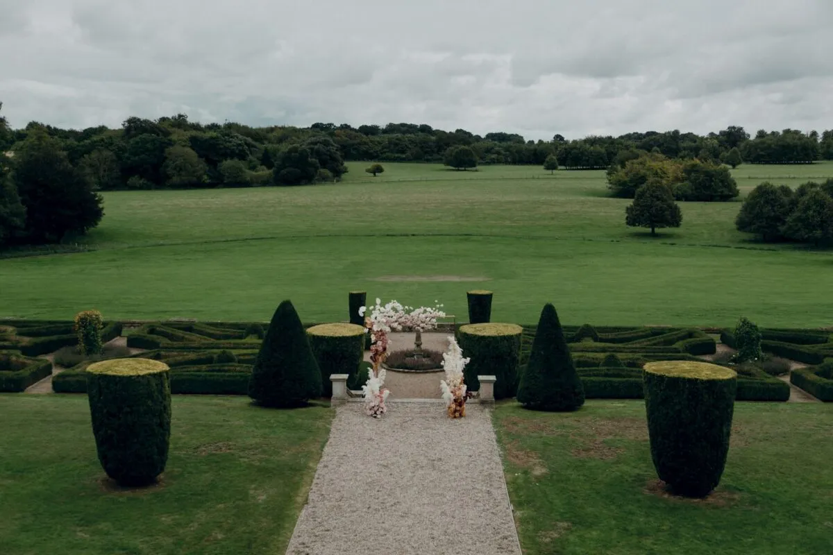 Hermoso jardín formal con setos y arreglos florales bajo cielos nublados (imagen de referencia)