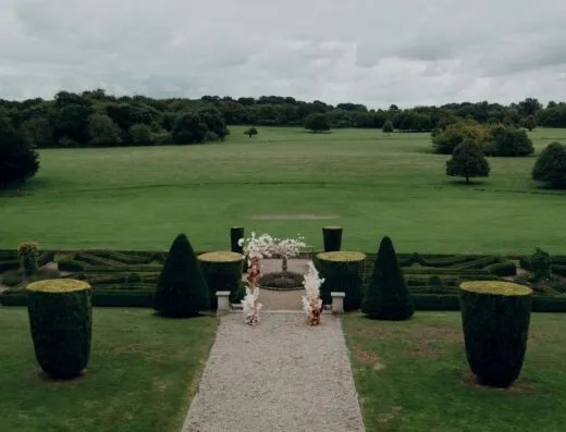Hermoso jardín formal con setos y arreglos florales bajo cielos nublados.