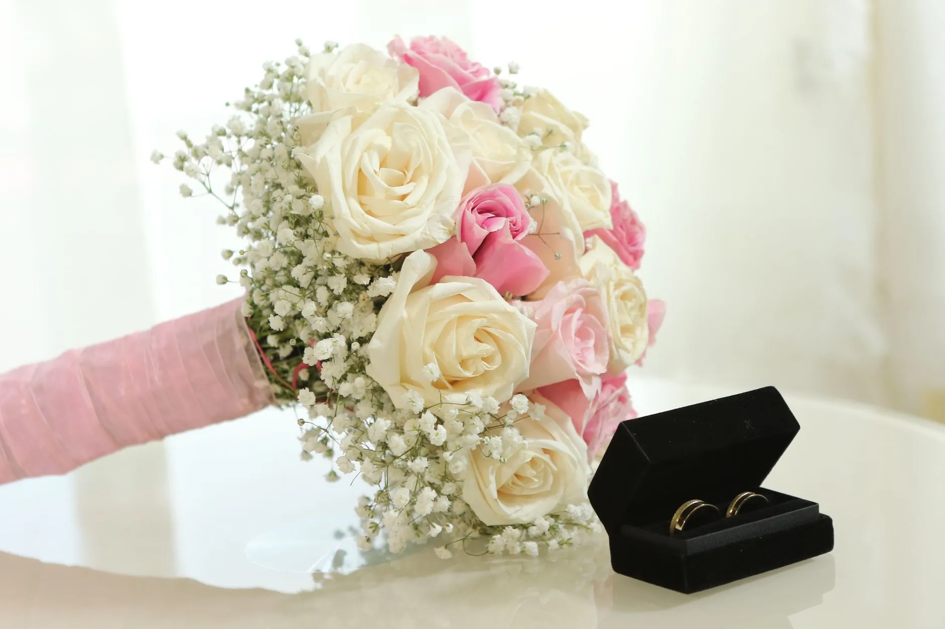 Hermoso ramo de boda de rosas y gypsophila con anillos de boda en una caja (imagen de referencia)