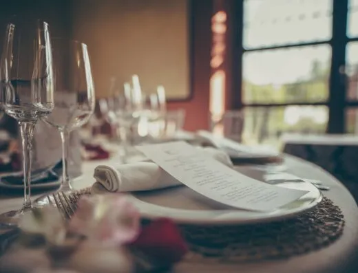 Un acogedor montaje de mesa para cenas elegantes en interiores, con vajilla elegante y un menú estiloso bajo una cálida iluminación.