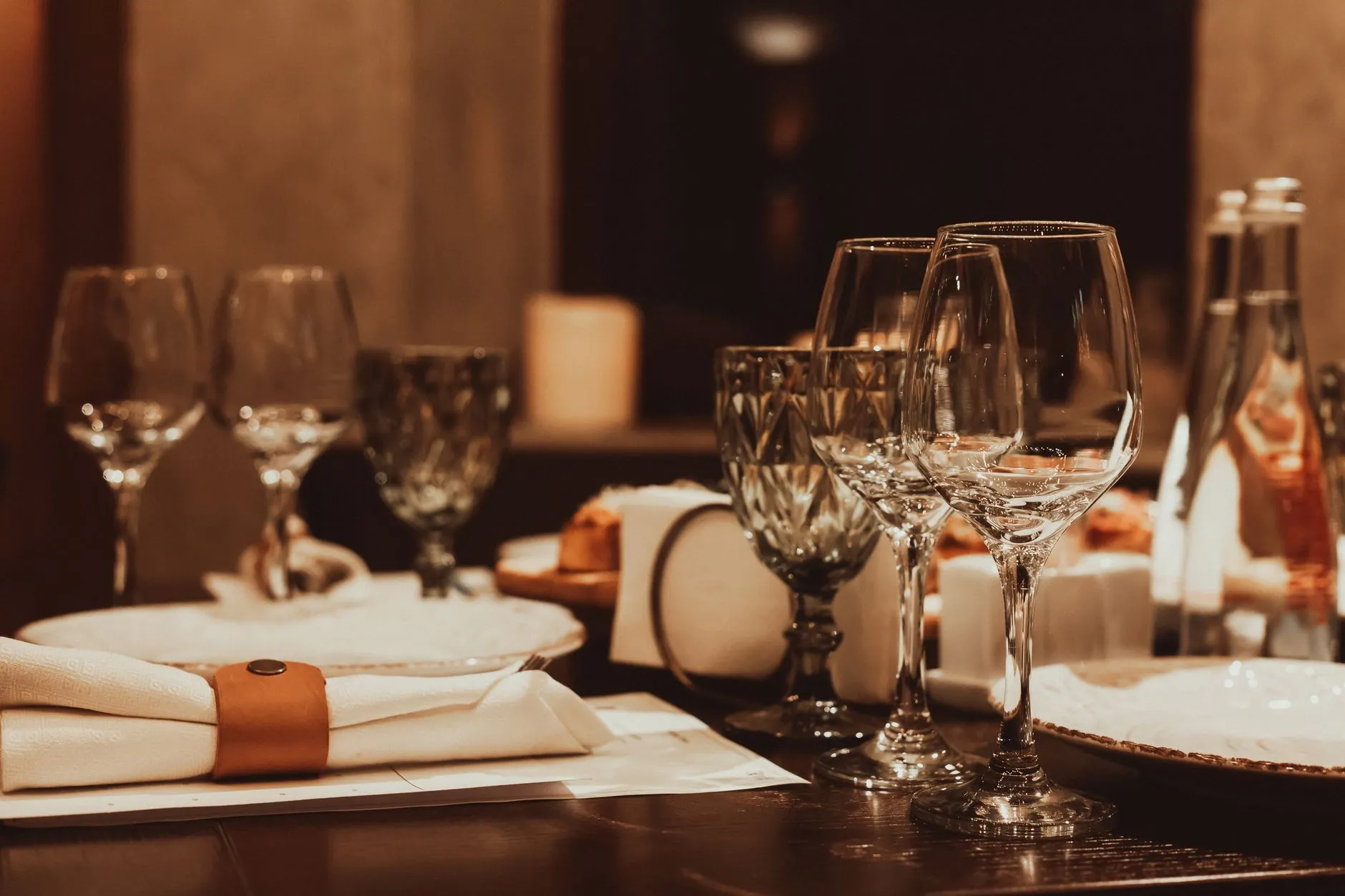 Arreglo de mesa de cena sofisticado con cristalería y luz de velas para una experiencia gastronómica de lujo.