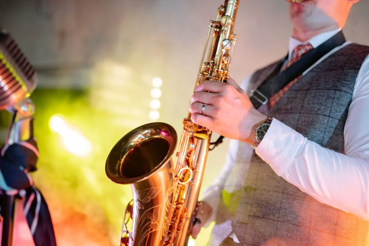 Un músico tocando el saxofón con pasión, mostrando talento bajo luces coloridas de escenario (imagen de referencia)