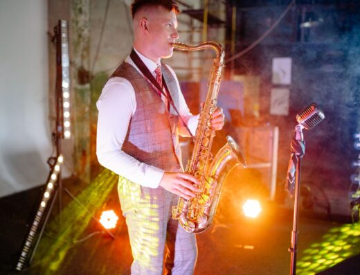 Un músico toca el saxofón en un escenario iluminado y con humo.