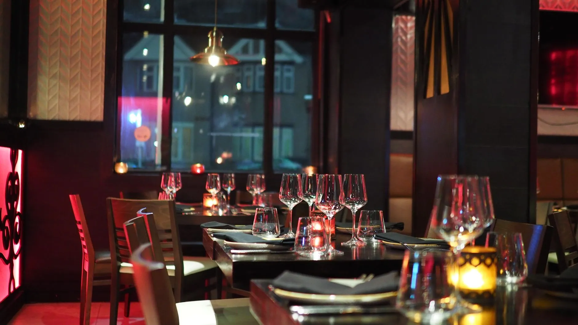 Un interior de restaurante sofisticado con una elegante mesa y luz de velas ambiente, creando una atmósfera acogedora.