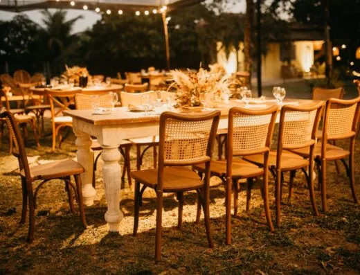 Mesas de recepción de boda al aire libre, bellamente arregladas bajo cálidas luces nocturnas.