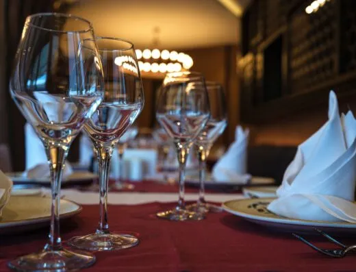 Primer plano de una mesa de cena bien puesta con copas de vino y servilletas dobladas, lista para una experiencia de alta cocina.