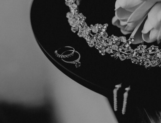 Primer plano de joyería de boda elegante en blanco y negro, que presenta anillos y una tiara.