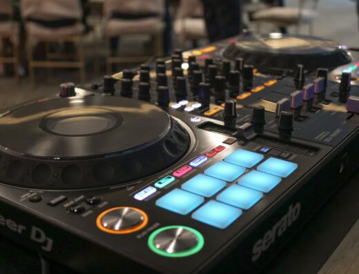 Primer plano de una consola de mezclador DJ Pioneer con botones y diales iluminados en un entorno de estudio.