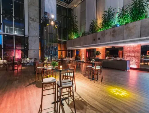 Lujoso salón de banquetes moderno con iluminación ambiental, suelos de madera y decoración elegante.