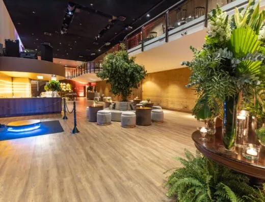 Amplio lounge del hotel con muebles modernos, plantas y un bar elegante, ideal para eventos o relajación.