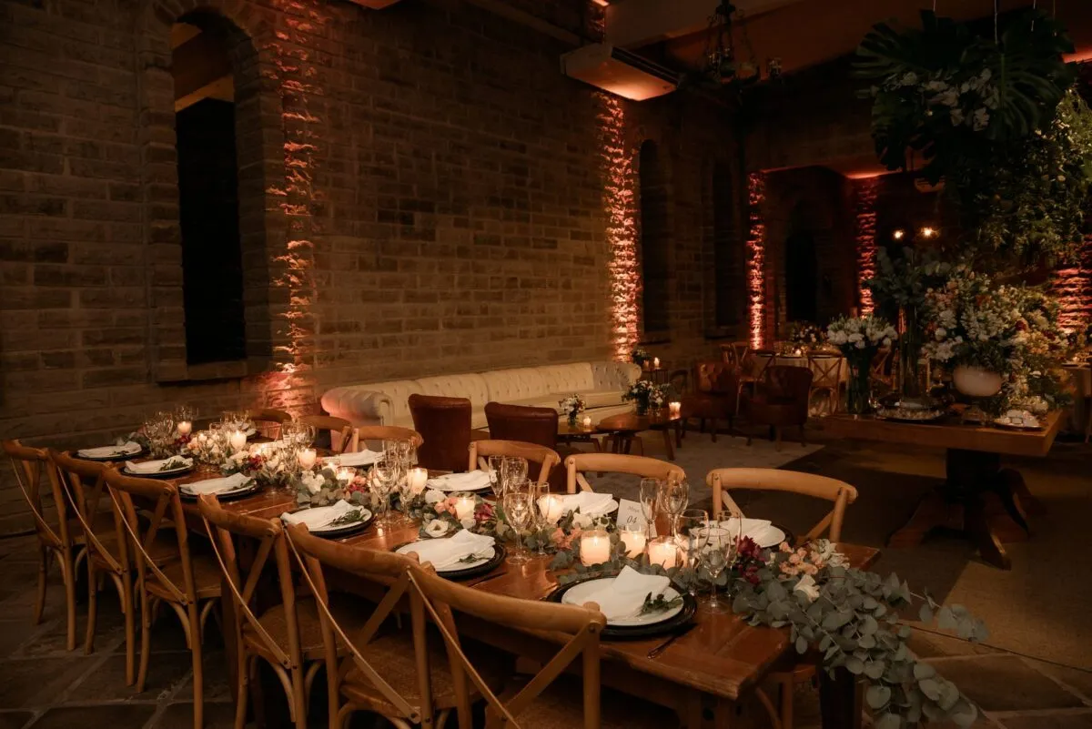 Salón de eventos rústico con mesas elegantemente decoradas para una reunión sofisticada (imagen de referencia)