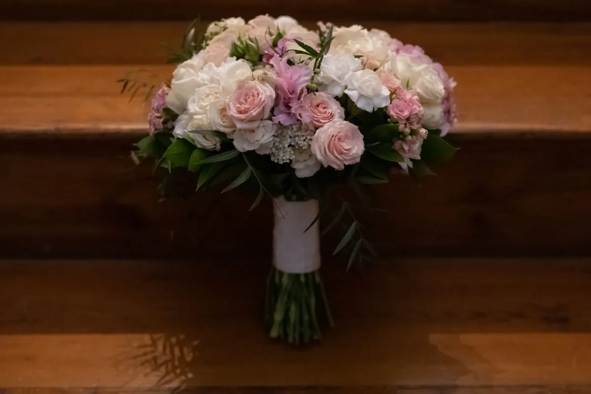 Un impresionante ramo nupcial con flores blancas y rosas dispuesto en escaleras de madera (imagen de referencia)