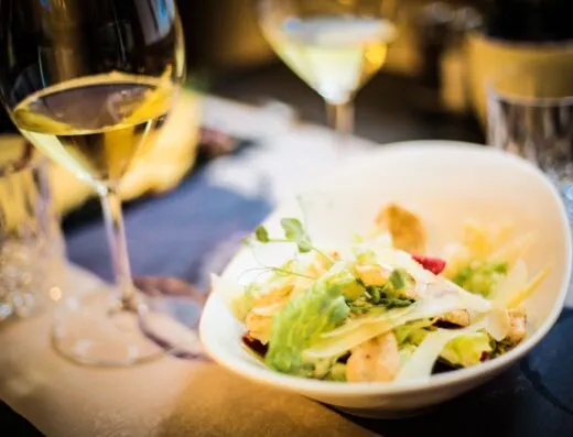 Un elegante ambiente gastronómico con una ensalada fresca y vino blanco, perfecto para una comida gourmet.