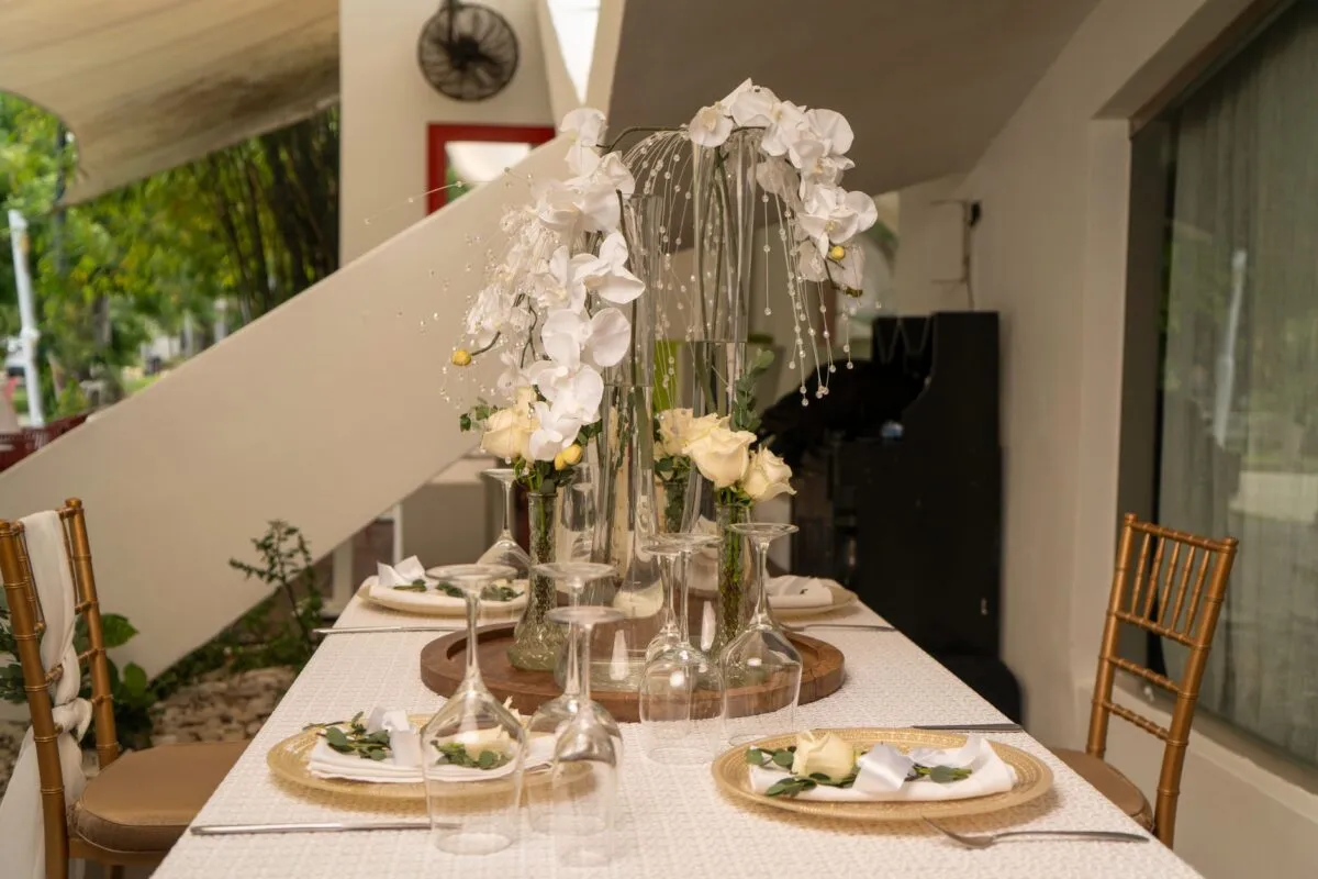 Elegante arreglo de mesa con flores blancas en jarrones altos, perfecto para bodas o cenas elegantes (imagen de referencia)