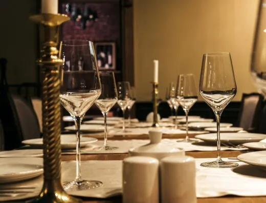 Configuración de mesa lujosa con copas de vino y candelabros en un elegante comedor.